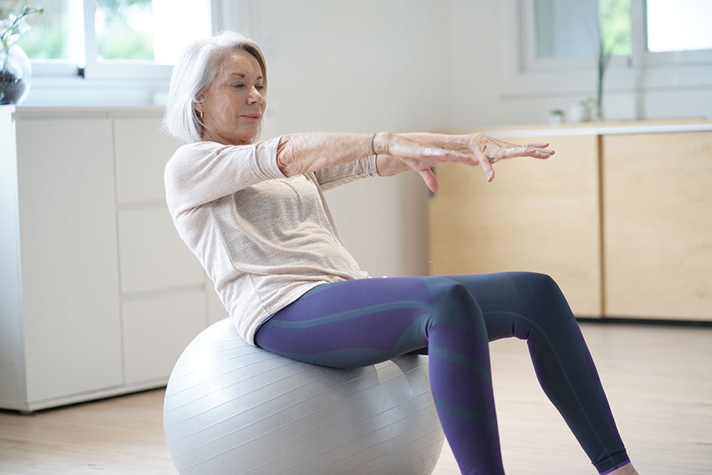 swiss-ball-abs Adobe stock photo of woman over 50 on Swiss ball doing abdominal curl
